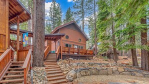 A cabin with a stone pathway leading to wooden stairs, surrounded by trees.