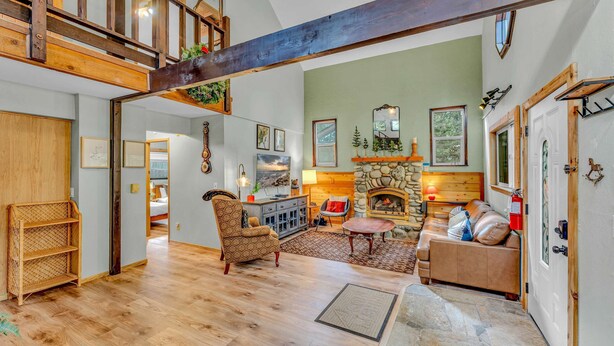 A spacious living room with a high ceiling, wooden beams, a fireplace, and a cozy seating area.