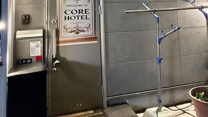 A hotel room with a metallic door, a welcome sign, a thermostat, and a towel rack. - COREHOTEL (Tokyo)