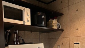A compact kitchen with a white refrigerator, a microwave, and a coffee maker on a shelf. - COREHOTEL (Tokyo)