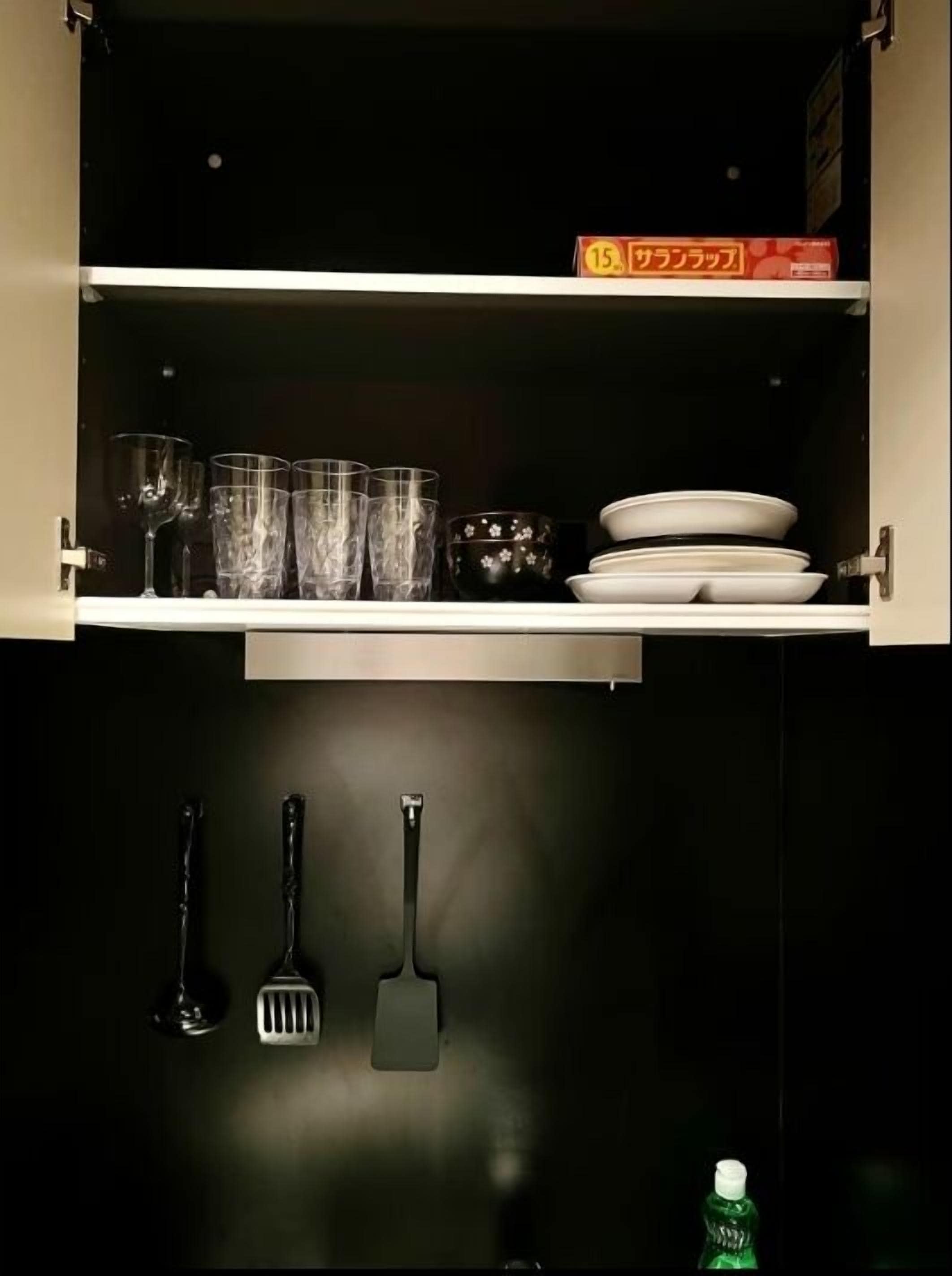 A kitchen cabinet with glassware, plates, and utensils.