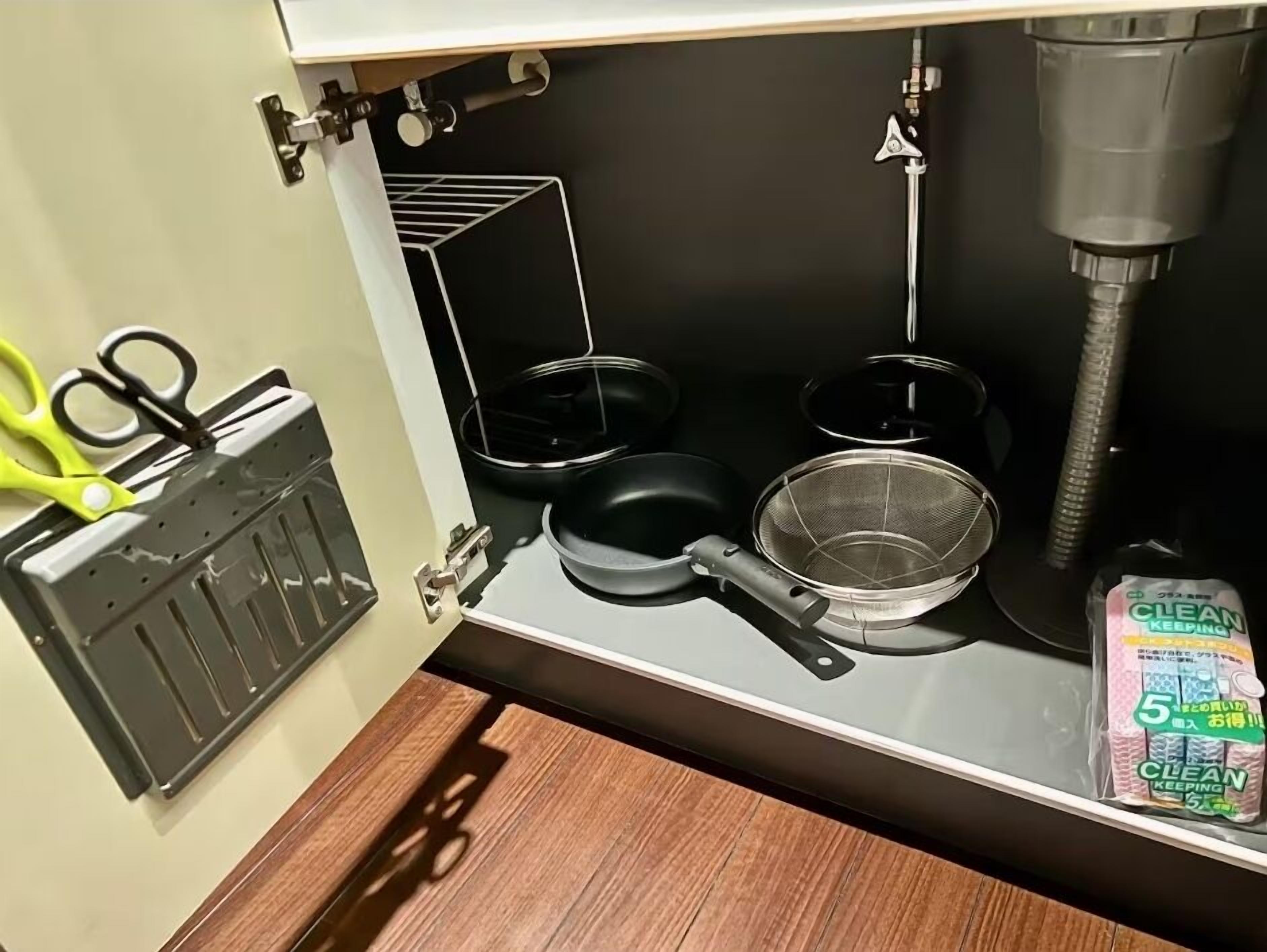 A kitchen with a black frying pan, a metal strainer, and a package of 'CLEAN KEEPING' wipes.