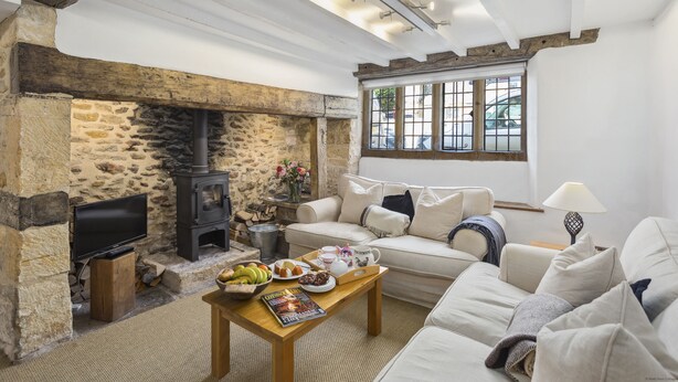 Una sala de estar acogedora con pared de piedra, chimenea, sofá y mesa de centro con alimentos para el desayuno.