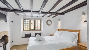 Un dormitorio con una cama de madera, una chimenea y una ventana con vistas.