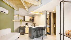 A modern kitchen with a central island, bar stools, and a built-in microwave. - Firenze Lofts (Medellín)