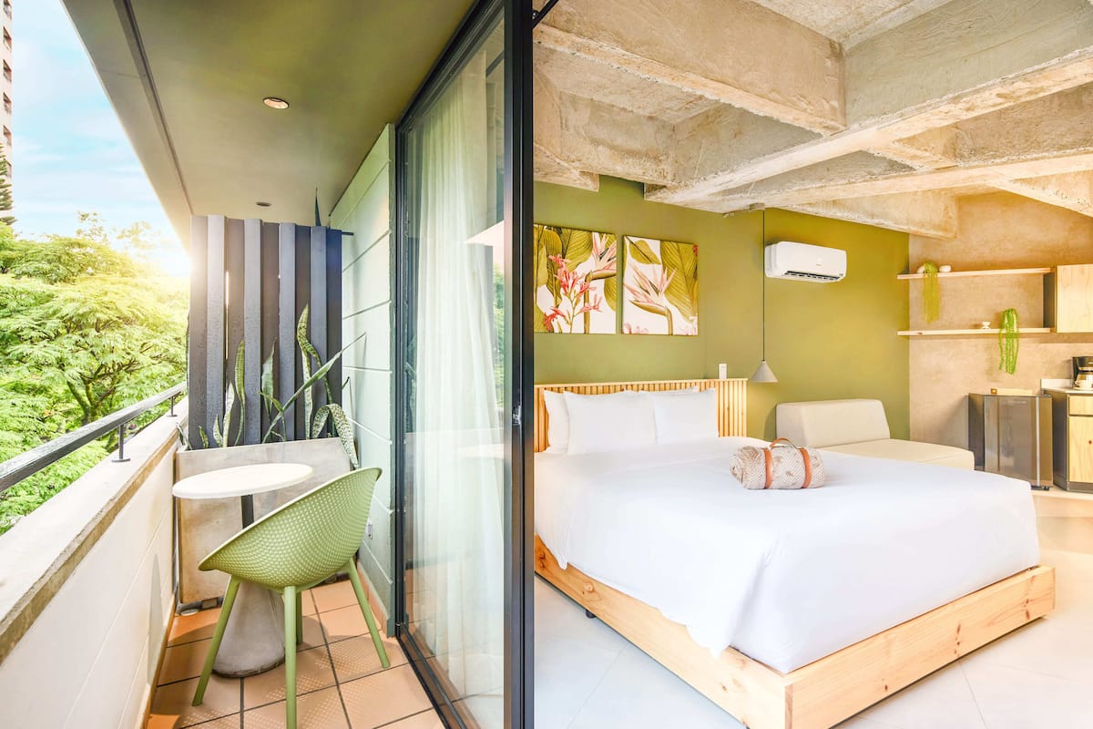 Un dormitorio moderno con una cama grande, una mesita y una silla.