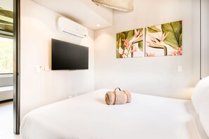 Hotellihuone, jossa on sänky, seinälle asennettu televisio ja ikkuna.