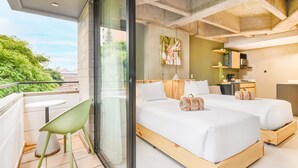 A modern hotel room with a balcony, a bed with white linens, a small table, and a chair. - Firenze Lofts (Medellín)