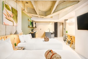 A modern hotel room with a large bed, a desk, a chair, and a small kitchenette. - Firenze Lofts (Medellín)