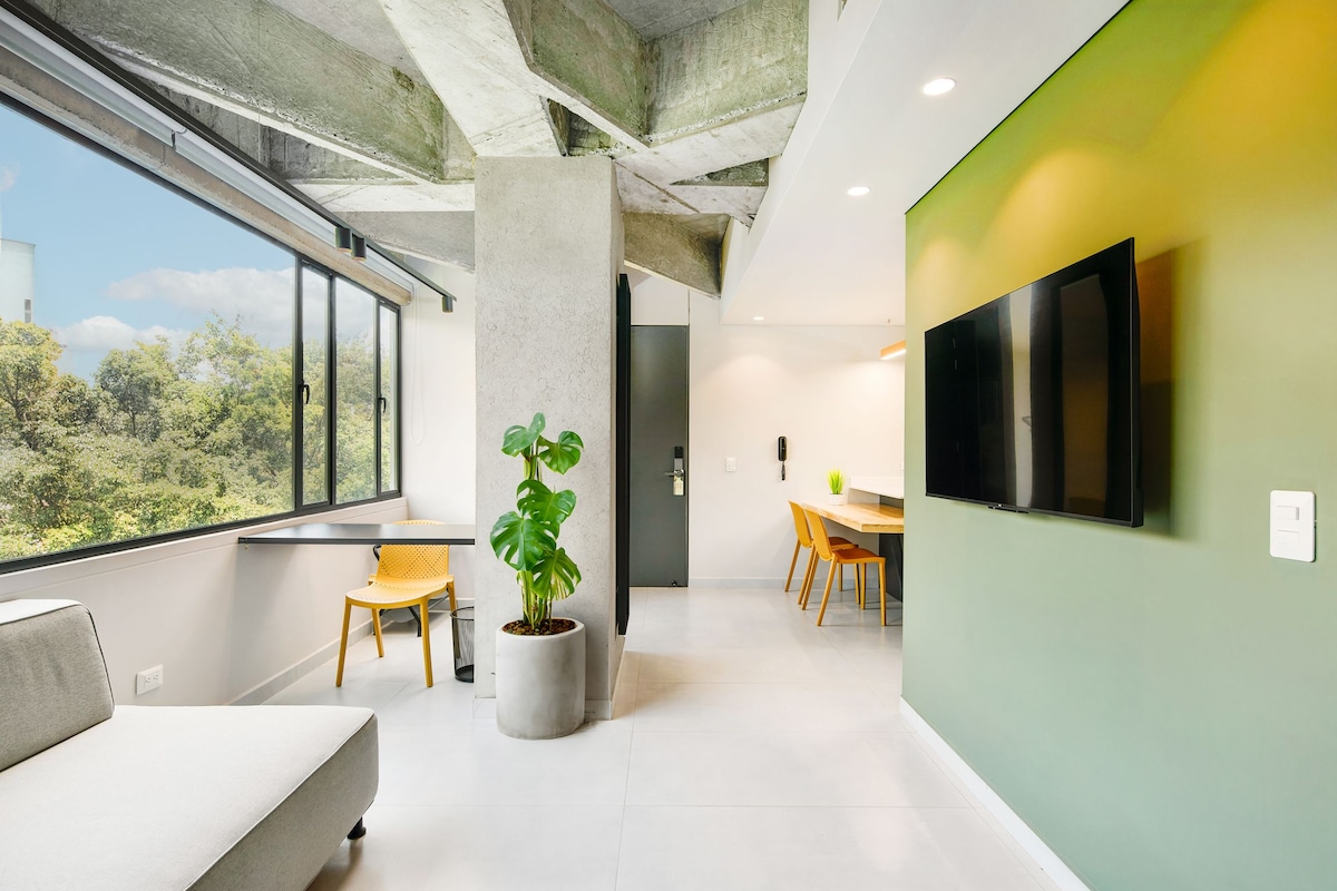 A modern interior with a large window, a potted plant, a sofa, a dining area, and a flat-screen TV.