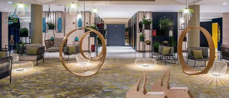 A spacious lobby with modern furniture, hanging light fixtures, and a patterned carpet.