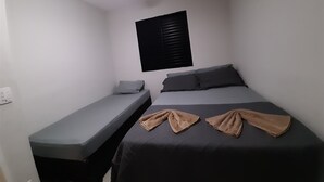 Eine kleine, einfache Unterkunft mit einem Bett, einer Sitzbank und einem Deckenventilator.