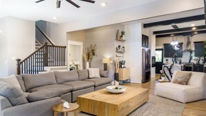 Ein modernes Wohnzimmer mit einem Ecksofa, einem Couchtisch aus Holz und einer Treppe, die in eine andere Ebene führt.