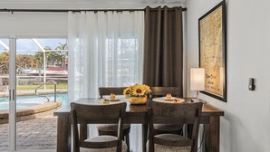 Un comedor con una mesa preparada para cuatro personas, un jarrón con girasoles y un mapa enmarcado en la pared.