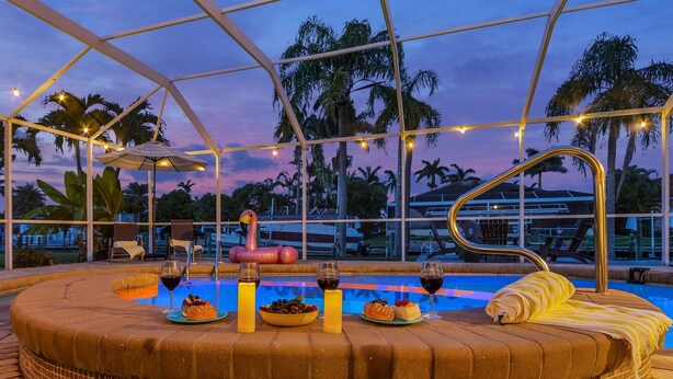 Zona junto a la piscina con jacuzzi, sillones de descanso y vistas al atardecer.