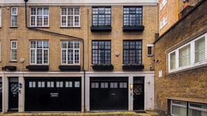 Edificio a più piani con ingresso per garage, facciata in mattoni e finestre con cornice nera.