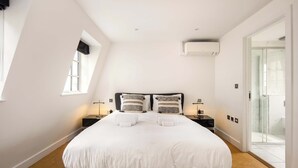 Una camera da letto moderna con un letto grande, lampade ai comodini, una finestra e un condizionatore d'aria.