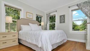 Quarto com uma cama grande, duas mesas de cabeceira com abajures, um penteadeira e uma janela com cortinas.