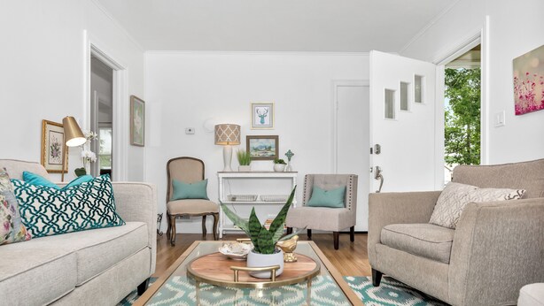 Sala de estar com sofá bege, poltrona estampada, mesa de centro com uma planta e lareira decorada.