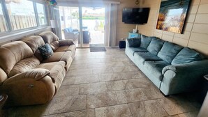 A living room with two sofas, a television, and a painting on the wall. - Key Colony Beach House with Cabana Club membership (Key Colony Beach)