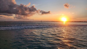 A sunset over a calm sea with a distant shoreline and a pier. - Key Colony Beach House with Cabana Club membership (Key Colony Beach)