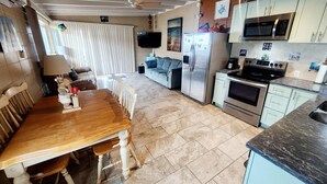 A compact kitchen with a refrigerator, microwave, oven, and a dining area with a wooden table and chairs. - Key Colony Beach House with Cabana Club membership (Key Colony Beach)