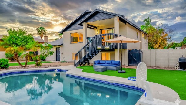 Una casa moderna de dos plantas con piscina, un porche cubierto y una escalera que conduce al piso superior.