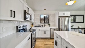 Una cocina moderna con armarios blancos, electrodomésticos de acero inoxidable y piso de madera.