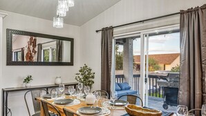 Un comedor con una mesa de madera dispuesta para seis personas, un espejo grande y vistas al exterior.