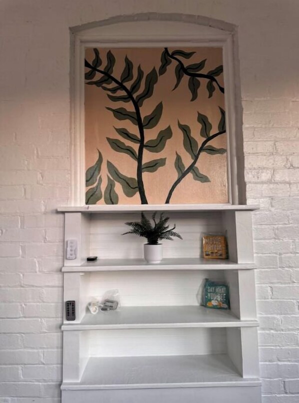 A white brick fireplace with a decorative leaf painting above it.