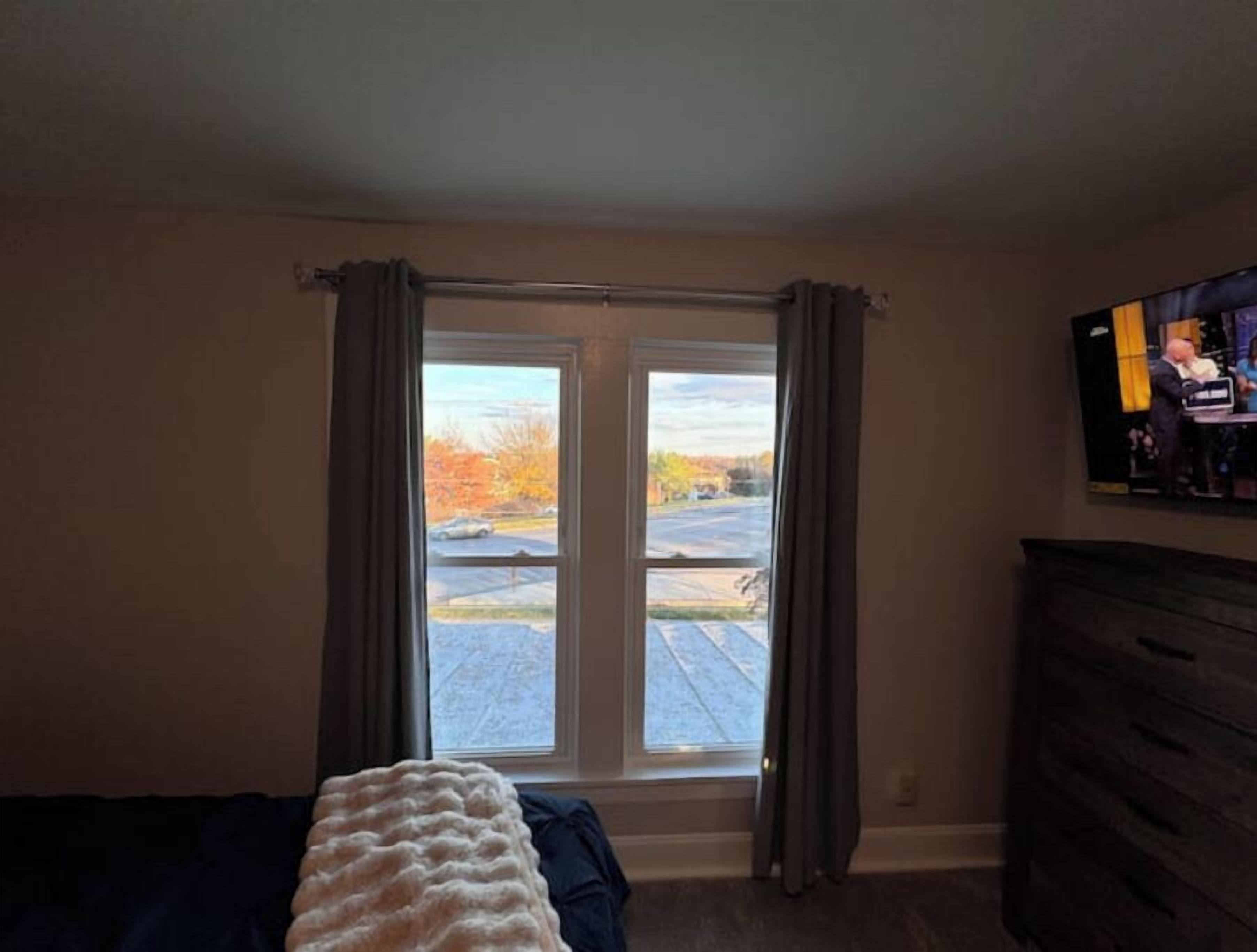 A bedroom with a bed, a dresser, and a TV on the wall.