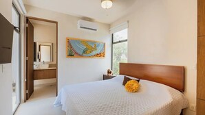 A bedroom with a large bed, a painting on the wall, and a window providing natural light. - Beautiful 2 Bedroom Apartment (Tulum)