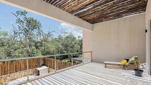 A balcony with a wooden ceiling, a stone wall, and a metal railing. - Beautiful 2 Bedroom Apartment (Tulum)