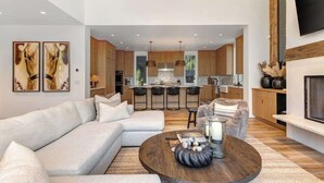 A modern living room with a sectional sofa, a round coffee table, and a kitchen in the background. - Abode at River Run, mountain modern, Ketchum (Ketchum)