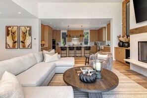 A modern living room with a sectional sofa, a round coffee table, and a kitchen in the background.