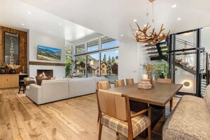 Un comedor moderno con una mesa de madera, sillas acolchadas y una chimenea.