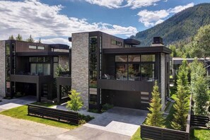 A modern two-story house with large windows, a stone facade, and a well-maintained lawn.