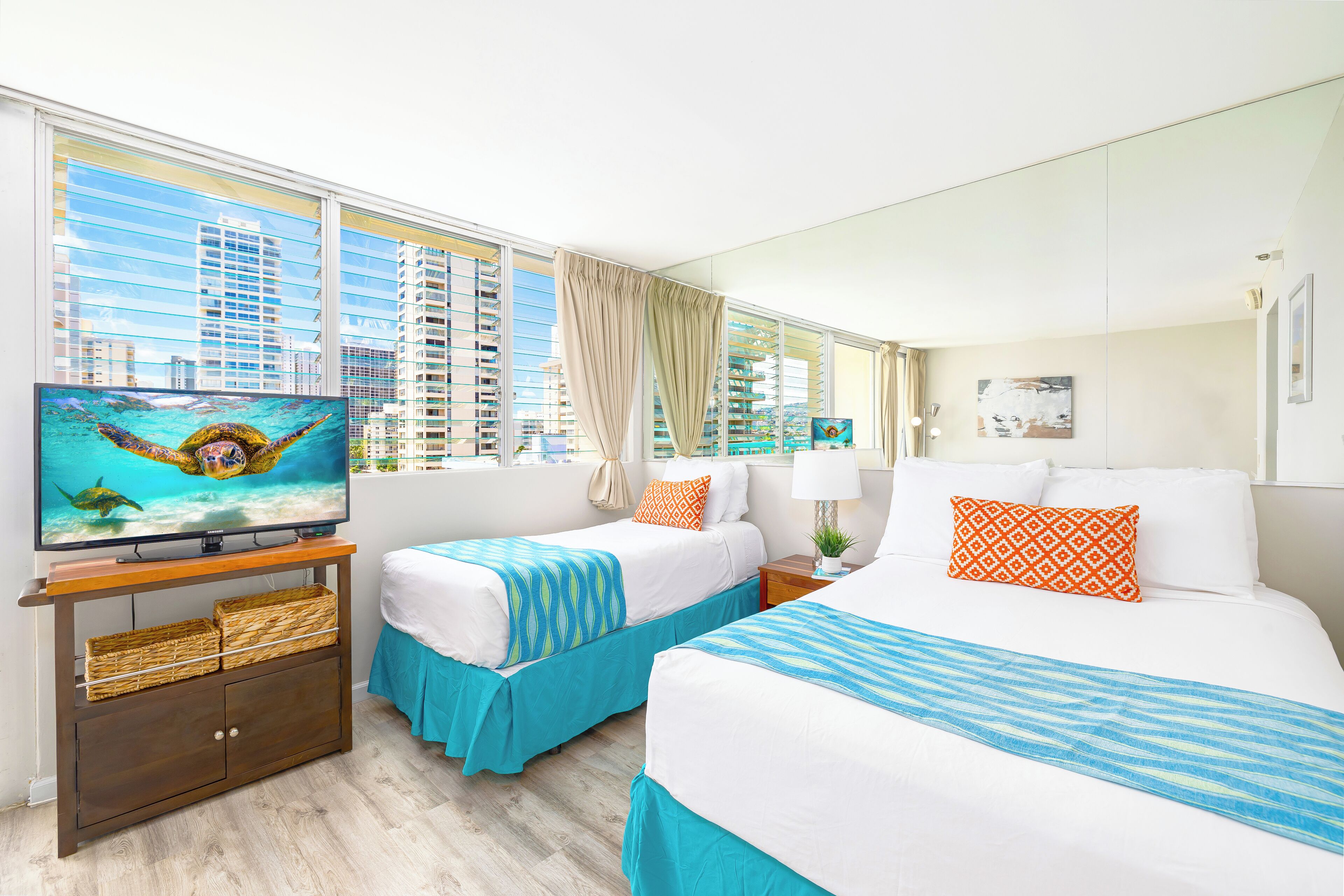A hotel room with two beds, a TV on a wooden stand, and a large window with a city view.