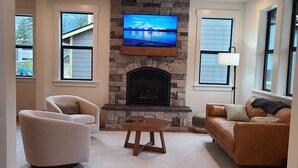 Ein Wohnzimmer mit Kamin aus Stein, einem darüber angebrachten Flachbildfernseher, zwei Sofas und einem Couchtisch.
