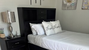 Un dormitorio con cama, mesitas de noche, una lámpara y una alfombra estampada.
