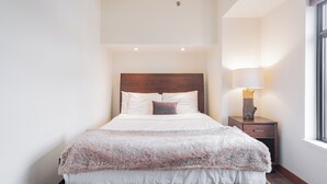 A neatly made bed with a fluffy blanket, a wooden headboard, and a bedside lamp. - Moscato-Ski-In/Ski-Out (A Condo at Carleton Lodge) (Whistler)