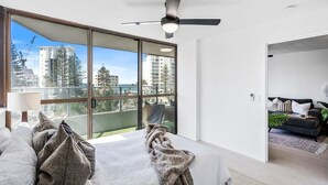 Ein modernes Schlafzimmer mit großem Fenster, Deckenventilator und Blick auf die Stadt.