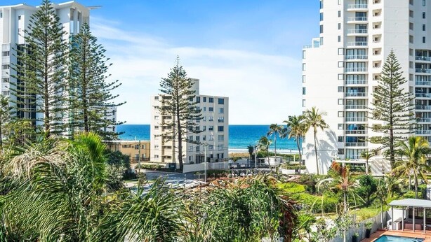Ein Hochhaus-Hotel mit mehreren Etagen, einem Poolbereich und Blick auf das Meer.