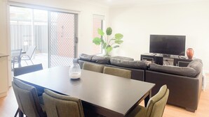 Una sala de estar con sofá, televisión y una mesa de comedor con sillas.