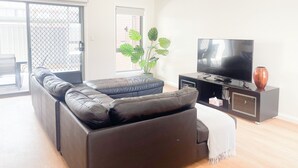Una sala de estar con un sofá modular, un televisor de pantalla plana y una planta en maceta.