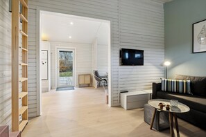Ein modernes Wohnzimmer mit einer Couch, einem Couchtisch, einem Fernseher und einem Bücherregal.