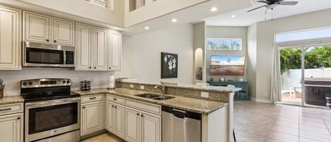 A spacious kitchen with white cabinetry, stainless steel appliances, and a granite countertop.