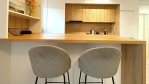 Een moderne keuken met houten kastjes, een ingebouwde oven en een bar met twee stoelen.