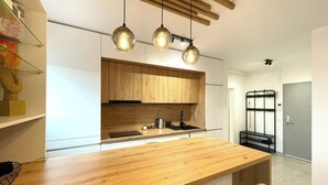 Een moderne keuken met houten kastjes, een houten aanrechtblad en hangende lampen.