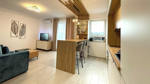 Een moderne woonkamer met een bank, een televisie en een houten scheidingswand.